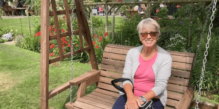 Trudy sitting on a swing bench in a garden