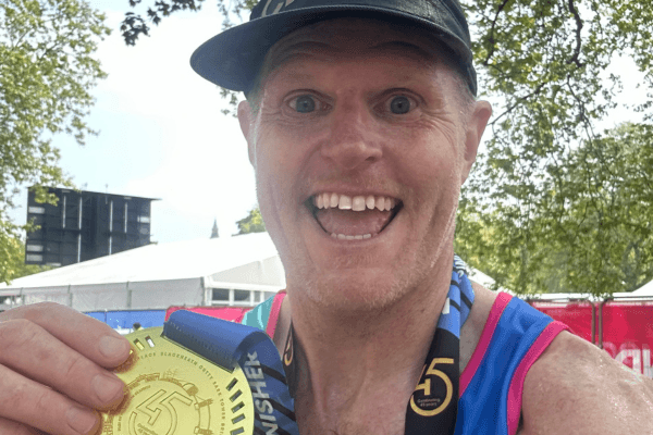 Tom, smiling, with his medal for completing the London Marathon in 2025.