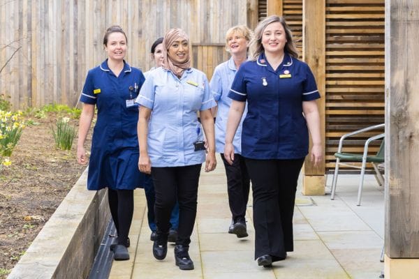 A group of five of the Martlets care team walking outside the hospice building