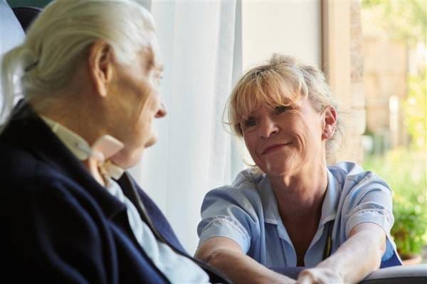 a member of the care team at Martlets sitting with a patient and smiling at them