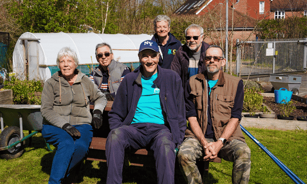 Group of six gardening volunteers - four men, two women, including Alison who has grey hair. All wearing gardeng gear.
