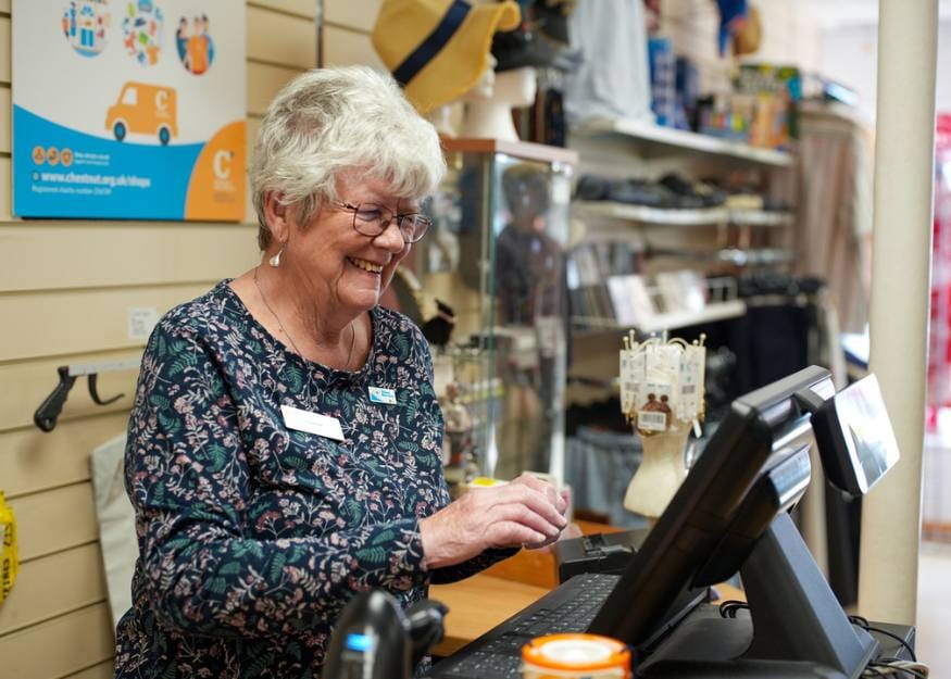 Liz, a retail volunteer using the till behind the counter at a Chestnut Tree House charity shop