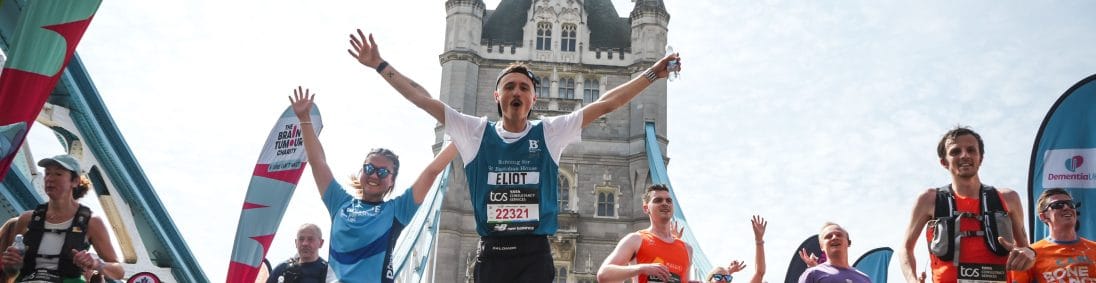 A runner raises his arms as he crosses Tower Bridge in the London Marathon 2026