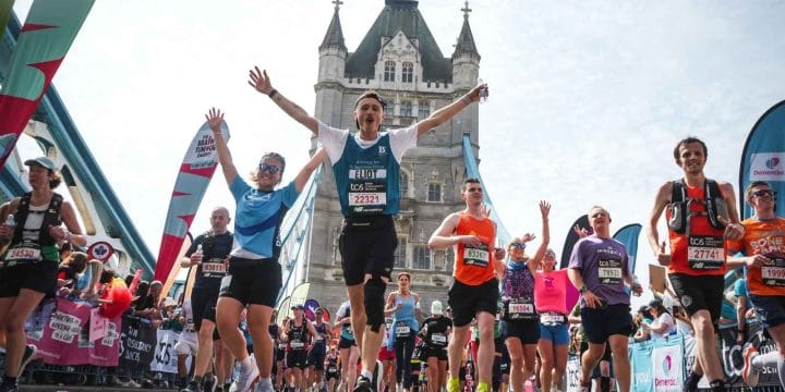A runner raises his arms as he crosses Tower Bridge in the London Marathon 2026