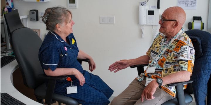 John, a volunteer on Martlets Inpatient unit, sitting with a member of staff at the reception desk