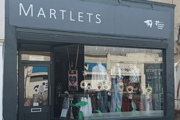 The exterior of the Martlets charity shop on brighton road, with dark grey frontage and display of sunflowers in the window