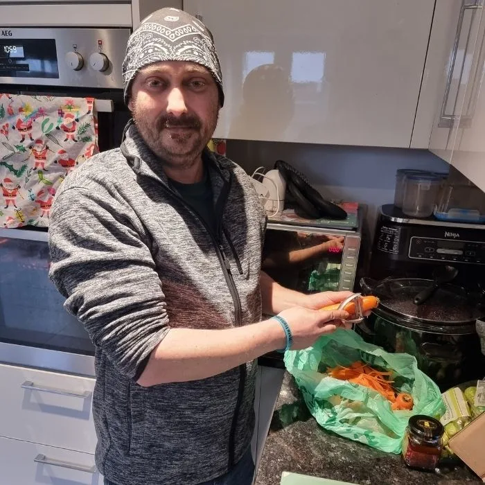 Dan peeling a carrot in the kitchen
