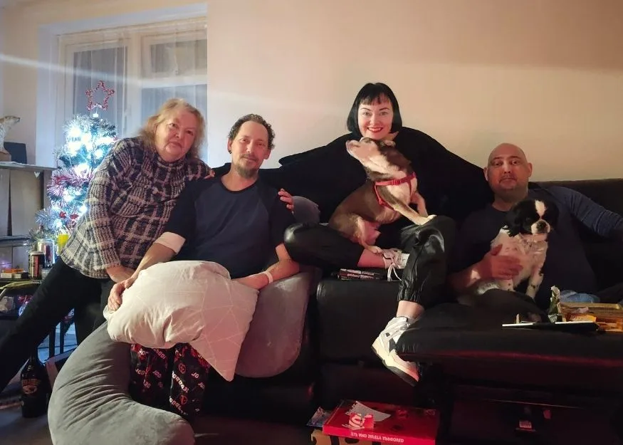 Carl, Marie, Dan and their mum posing for a photo with a christmas tree in the background