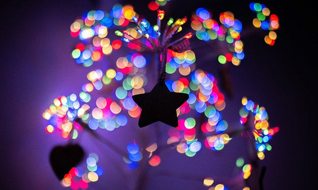 star shaped tree ornament with multicloured fairy lights in the background