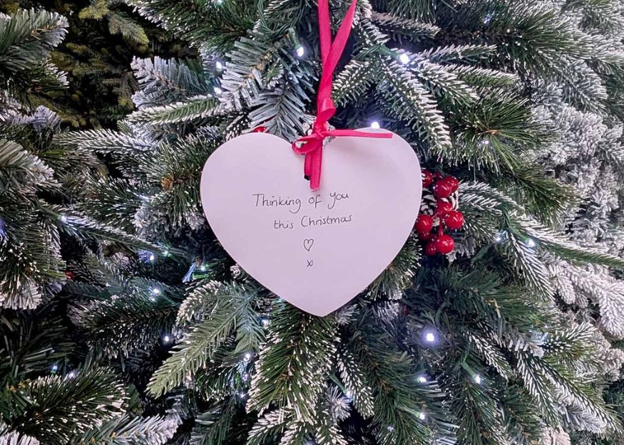Christmas tre with card heart with handwritten message reading "Thinking of you this christmas"